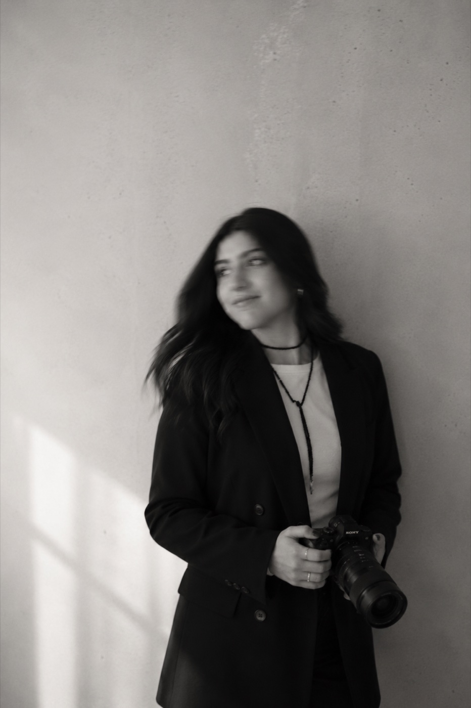 Mariana Olvera apoyada en un muro, sosteniendo su cámara